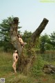 A couple of naked women sitting on top of a tree.