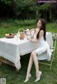 A woman sitting at a table with a basket of fruit.