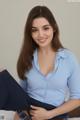 A woman in a blue shirt is sitting on a bed.