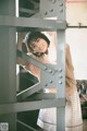 A woman leaning against a metal structure in a room.