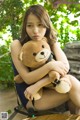 A woman sitting on a bench holding a teddy bear.