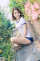 A woman sitting on a wooden bench in a garden.