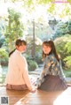 Two young women sitting on a wooden deck in a garden.