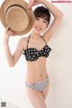 A woman in a bikini and a straw hat posing for a picture.