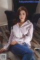 a woman sitting on the floor wearing a striped shirt and jeans