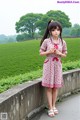 A woman in a pink dress standing on a stone wall.