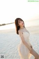 A woman in a white dress standing on a beach.