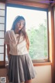 A young woman standing in front of a window.