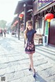 A woman in a black dress is walking down the street.