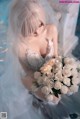 A woman in a wedding dress holding a bouquet of flowers.