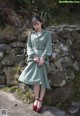 A woman in a green dress sitting on a stone wall.