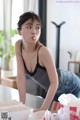A woman in a black top and blue jeans leaning over a table.