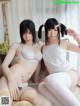 Two asian women in lingerie sitting on a bed.