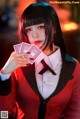 A woman in a red suit holding a deck of cards.