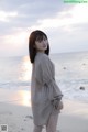 A woman standing on a beach next to the ocean.