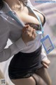 A woman in a white shirt and black skirt holding a blue id card.