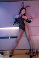 A woman in a black latex outfit holding a whip.