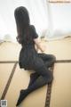 A woman in a black dress sitting on a tatami mat.