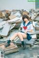 A woman in a school uniform sitting on a pile of rubble.