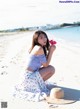 A woman sitting on a beach holding a flower.