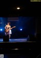 A woman playing a guitar on a stage.