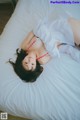 A woman laying on top of a white bed.