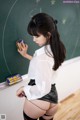 A woman standing in front of a blackboard holding a cell phone.