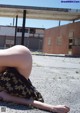 A woman laying on the ground in front of an abandoned building.