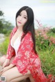 A woman in a red kimono sitting on the ground.