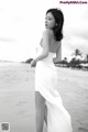 A woman in a white dress standing on a beach.