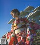 A woman in a colorful kimono standing in front of a building.