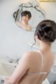 A woman standing in front of a mirror in a bathroom.