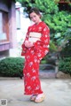 A woman in a red kimono standing in front of a building.