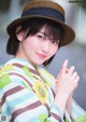 A woman in a kimono and a straw hat posing for a picture.