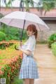 A woman in a school uniform holding an umbrella.