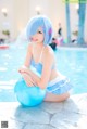 A woman in a blue bikini sitting on a blue ball.