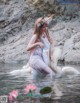 A woman in a white dress is standing in the water.