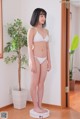 A woman in a white bikini standing on a scale.